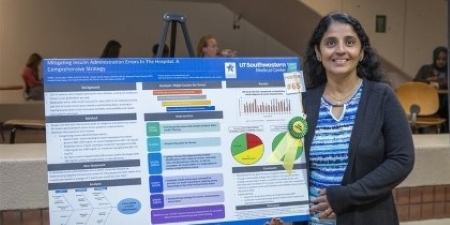 smiling woman with long hair stands next to research poster on easel