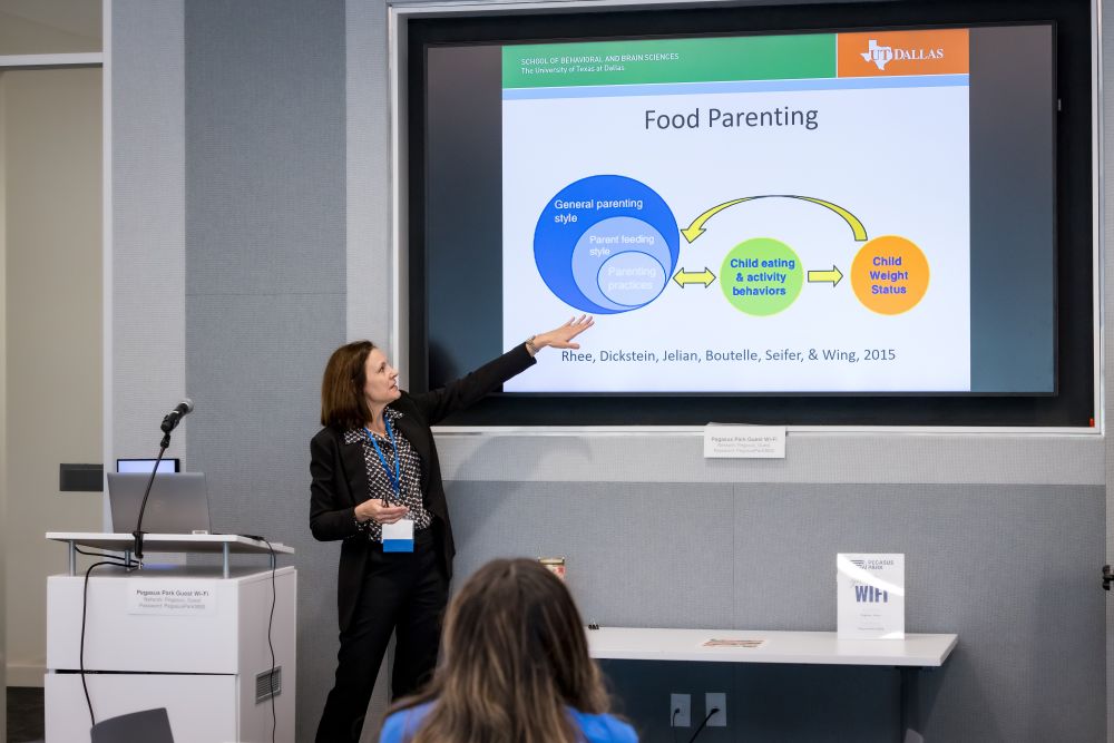 woman speaker points up at presentation slide projection about Food Parenting