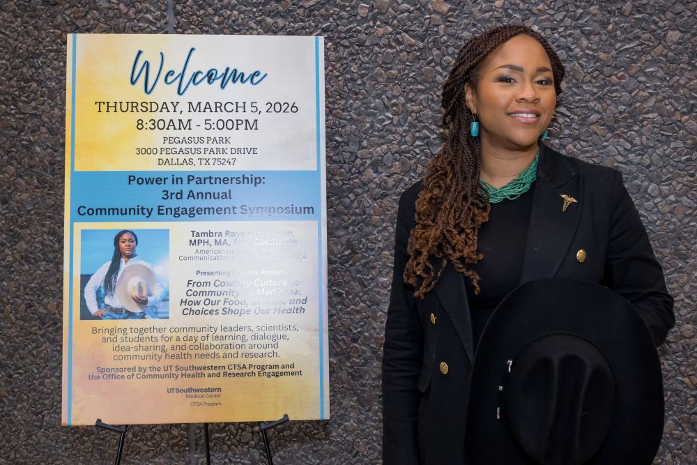 speaker Tambra Raye stands next to poster of her talk for Power in Partnership March 15, 2026 at UT Southwestern