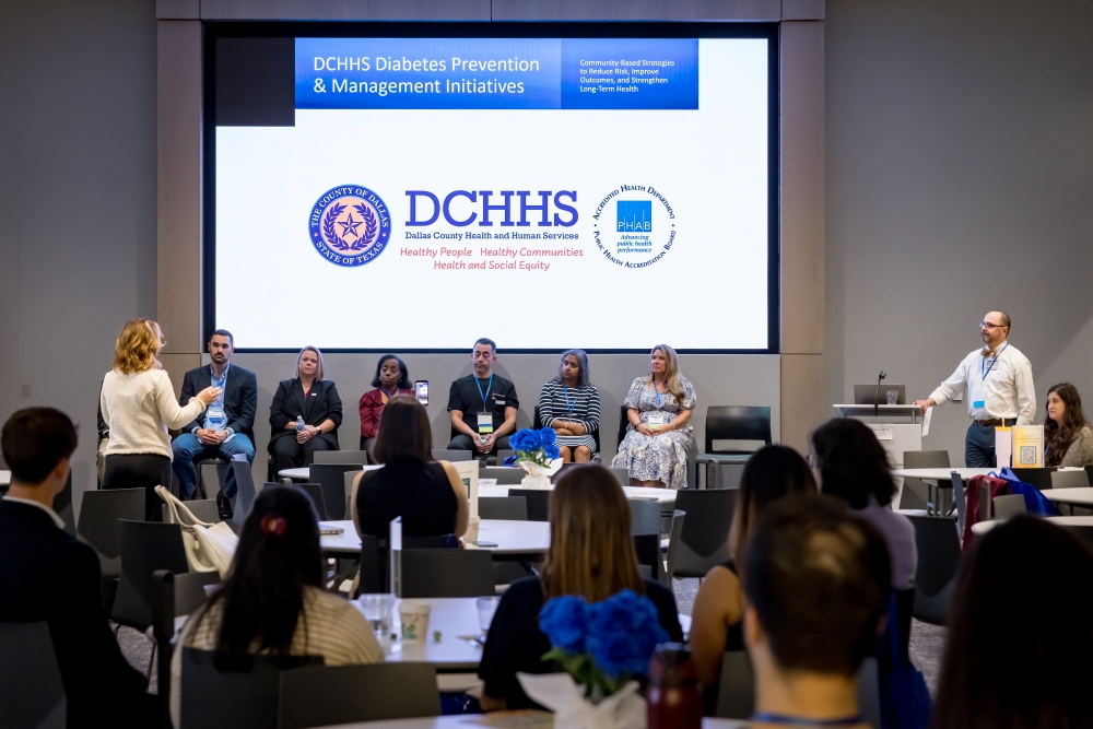 2 speakers man and woman stand at either end of stage with 6 panelists seated in the center under presentation screen displaying DCHHS Diabetes Prevention