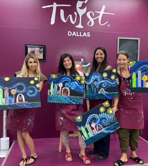 in front of Twist Dallas on red wall stand 4 smiling women holding their oil paintings