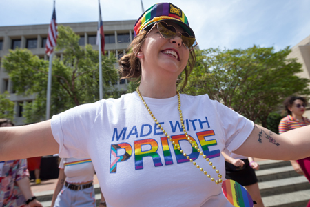 A woman wearing a T-shirt that says Made with Pride. The word Pride is filled with rainbow colors