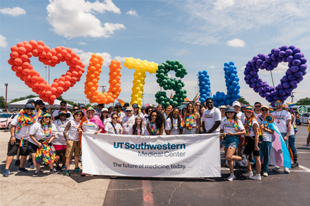 rainbow balloons and a group of people wearing rainbow attire