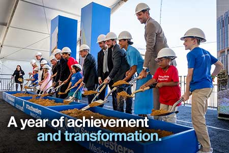 row of diverse people wearing white hard hats hold shovels over trough of dirt at UTSW groundbreaking; text: A year of acheivement and transformation