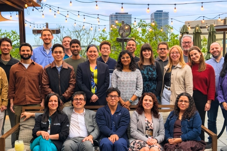 Large group of men and women seated and standing on a rooftop restaurant with the Dallas skyline in the background