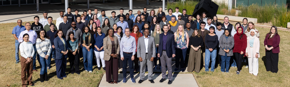 A group of men and women from different diverse backgrounds, taking a picture outside