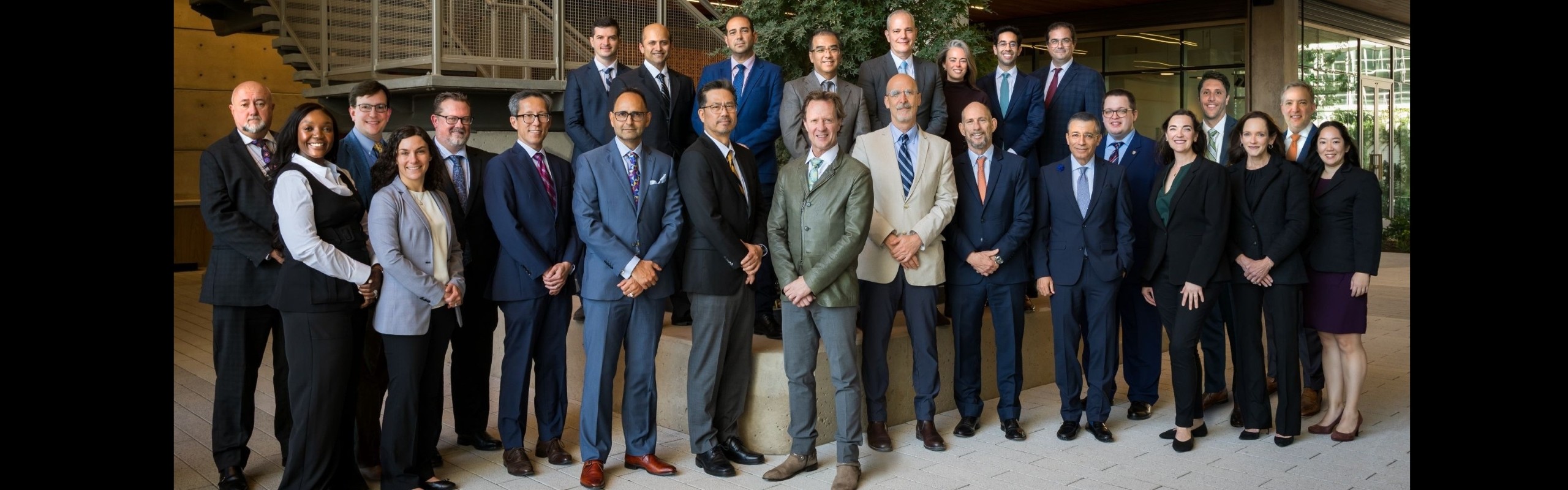 The entire Plastic Surgery Department, dressed up and posed in front of a large window.