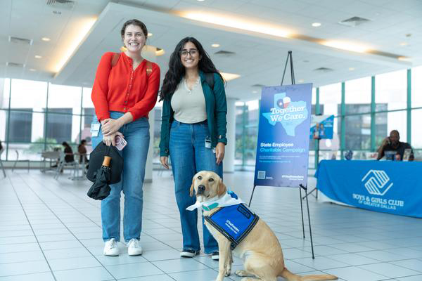 Two women pose with yellow lab, Tia