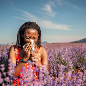 Photo of a woman sneezing in a field of flowers