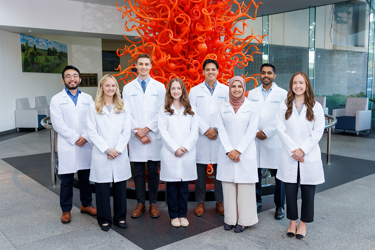 a group of men and women wearing white coats in an outdoor setting