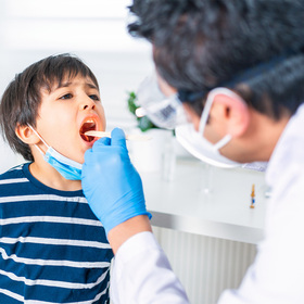 Photo of a doctor examining a child's open mouth