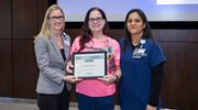 At the Health System Affairs event, Platinum pin recipient Sabrina Ortiz from the Ambulatory Clinical Heart and Vascular Center displays her certificate beside Traci d’Auguste, M.B.A., M.S.H.A., Vice President and CEO of William P. Clements Jr. University Hospital, left, and Mayra Avila, Supervisor of Medical Office Assistants.