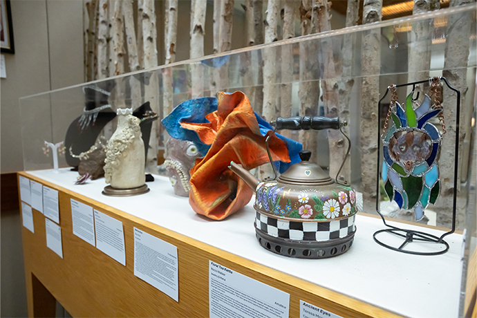 displayed jewelry and metal pieces in glass encased shelf with description cards on the wood below each