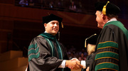 Alex Sternisha, M.D., Ph.D., shares a smile and a handshake upon accepting his diploma.