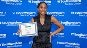 Gold pin recipient Italya Hutchinson from Research Regulatory Affairs is all smiles holding her certificate at the Academic Affairs ceremony.