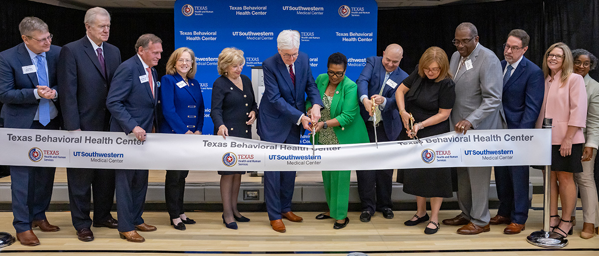 9 men and women, 3 with large scissors cutting a white ribbon. Texas Behavioral Health Center and UTSW logos.