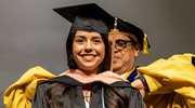 Alondra Olmos, M.P.H., is hooded by Dean Omer.