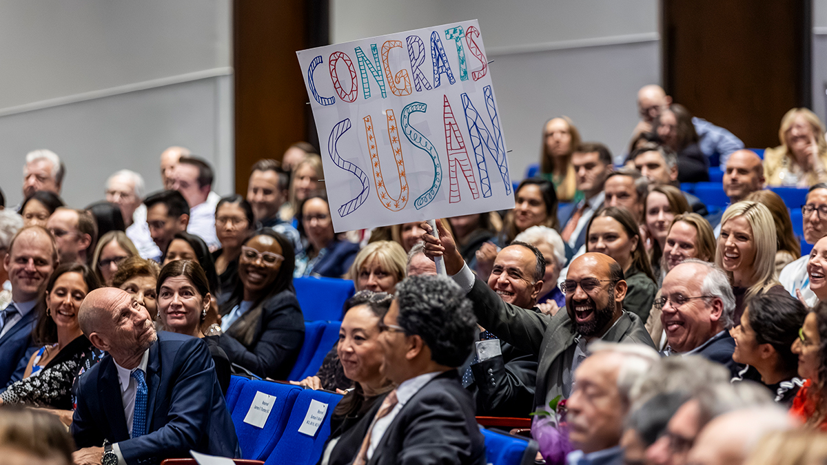 Audience member holds sign that reads, Contrats Susan.