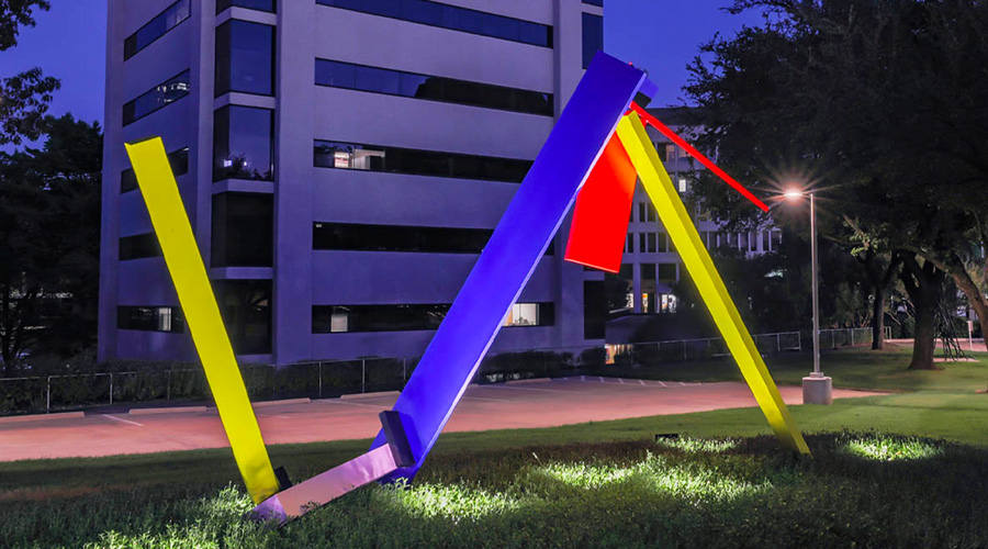 Lighted, multi-colored outdoor statue at night.