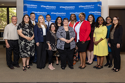 diverse group of 14 employees stand in front of blue UTSW backdrop
