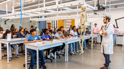 Dr. Tatara leads students in a review of a clinical case involving a young patient with arm pain due to a missing piece of bone caused by cancer. The students then experimented with diverse ways to make a mold in the shape of the patient’s missing bone.