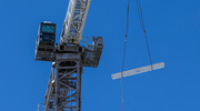 A construction crane raises the beam for final placement atop the hospital.