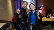 Office for Institutional Opportunity Director Dawn Cureton, M.B.A., left, and Program Coordinator Winnie Law pose with complimentary handheld flags at the Tribute to Veterans Celebration.