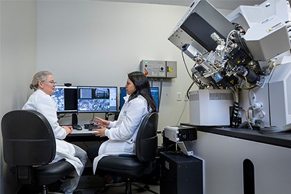 Two scientists confer in a laboratory, near a large hydra microscope.