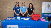 UTSW Employee Advisory Council members offer treats at their table.