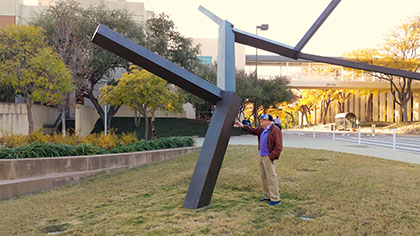Man admiring an outdoor bronze statue.
