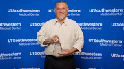 Mr.&nbsp;Flores, recipient of the Distinguished Service Award, holds his trophy in a photo op following the program. His job is to inspect and prepare the UTSW shuttle fleet before drivers begin their daily routes at 5 a.m. as well as support vehicles and equipment used by departments campuswide.
