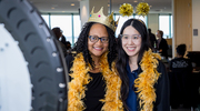 Angela Rollins, left, and Dalena Le of Radiation Oncology get into the spirit with colorful feather boas and hats at the Academic Affairs event.