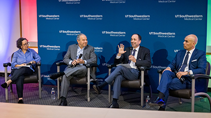 3 faculty members seated on stage with microphones