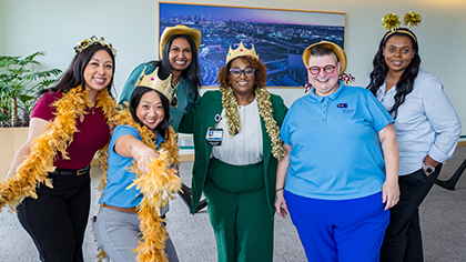 6 people wearing silly hats and feather boas.