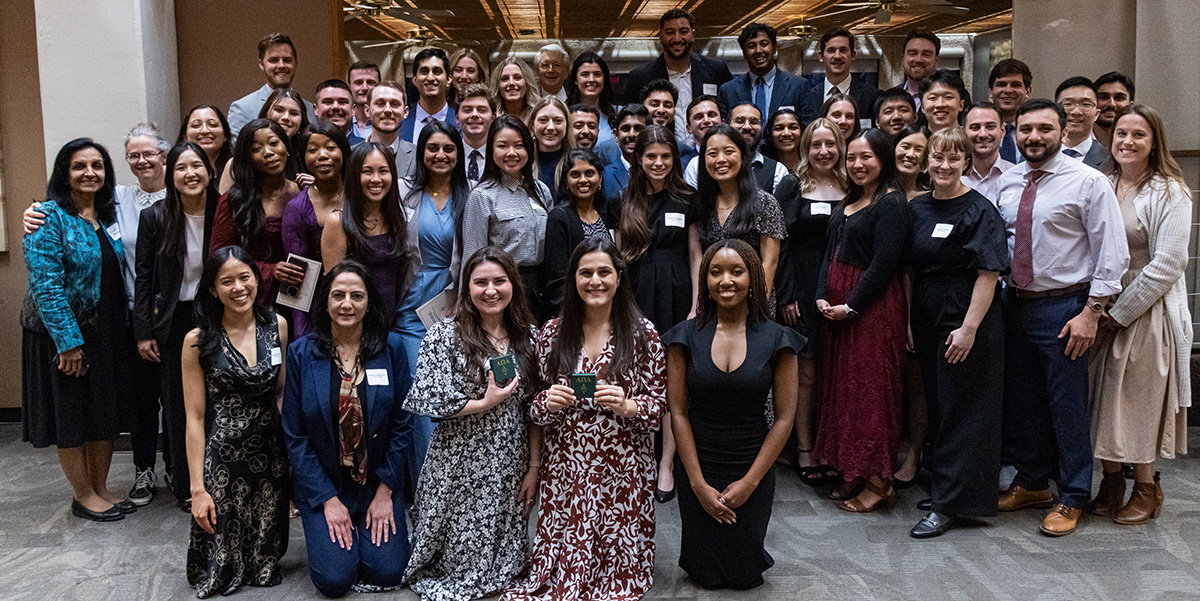 A large group of well dressed men and women pose together.