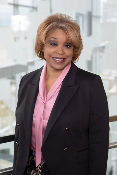 Woman with blonde hair, wearing black blazer and pink blouse