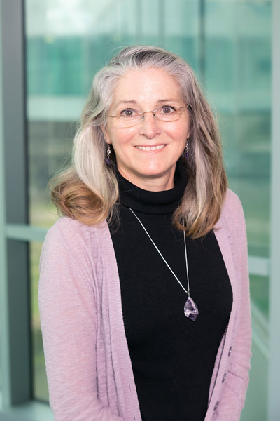 Woman with glasses, wearing pink carnigan and blue top