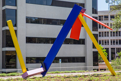 Large brightly colored linear sculpture in front of a building.