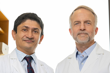 2 men in lab coats, dark hair Dr. Patel left and grey hair w beard Dr. Buszczak right