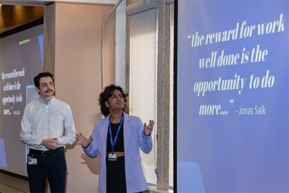 man and woman stand next to projection screen during presentation