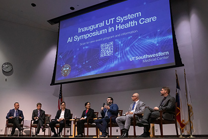 7 speakers seated on stage below projection screen