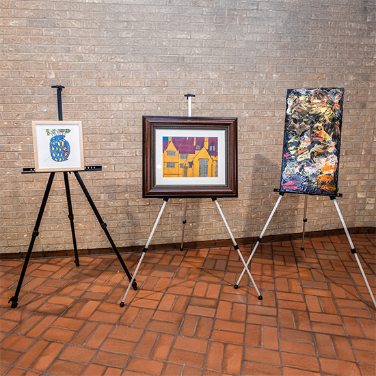 Three easels displaying paintings.
