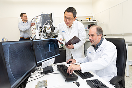 Two scientists in a lab examining results on a screen.