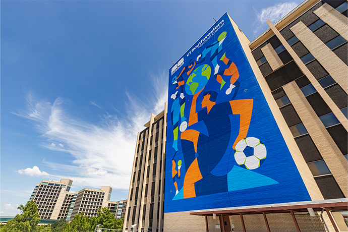 outdoor photo of FIFA mural on side of building, shot from ground up