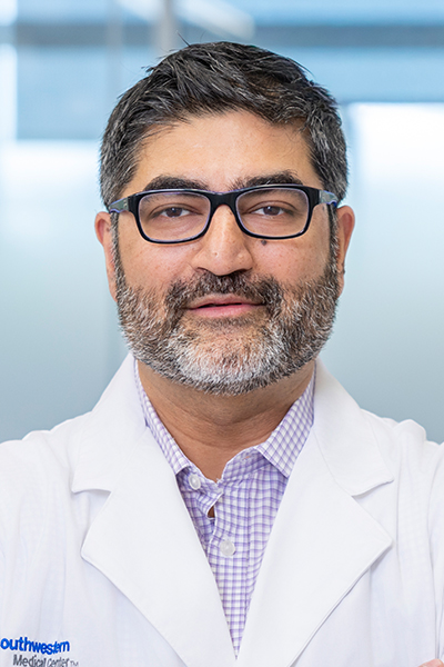 bearded man in lab coat wearing glasses