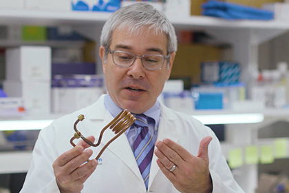 man with grey hair and glasses in white lab coat