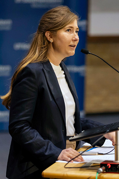 woman with long dark hair speaks from podium