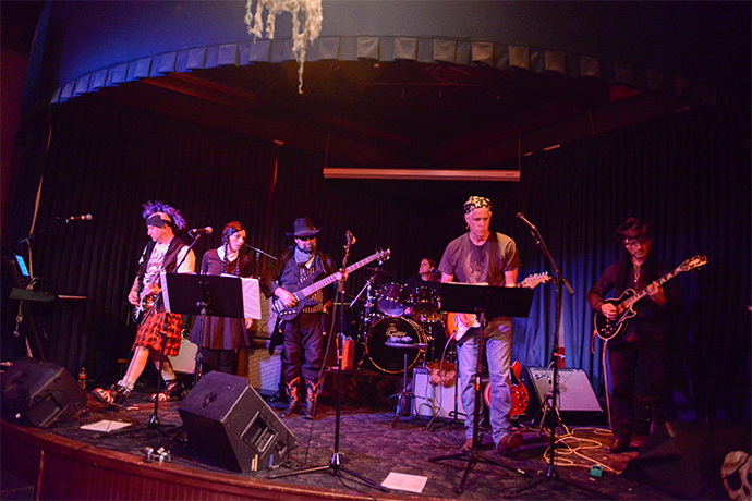 The band Transvactors performing on stage as a group.