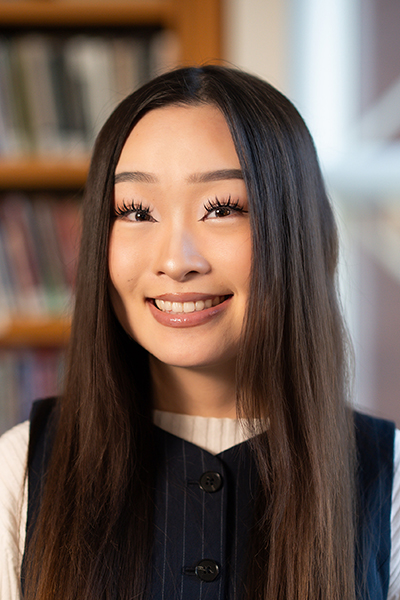headshot of woman with long dark hair in front of bookcase