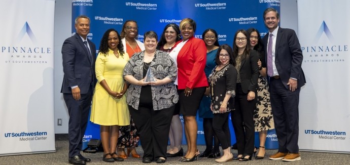 diverse group of 11 employees pose in front of Pinnacle Awards and UTSW banners